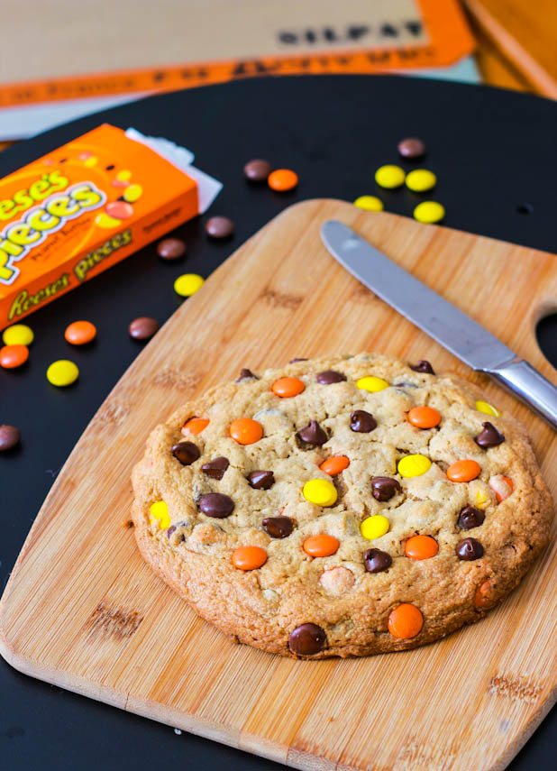 one giant peanut butter Reese's Pieces cookie on a wood board