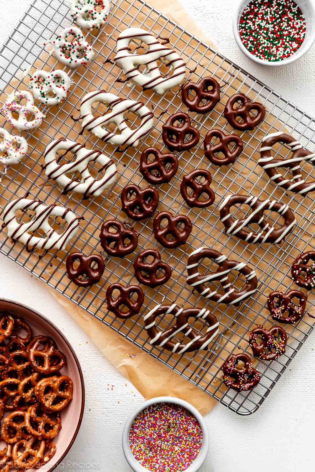 various chocolate covered pretzels on cooling rack including some with white chocolate, chocolate drizzles, and sprinkles.