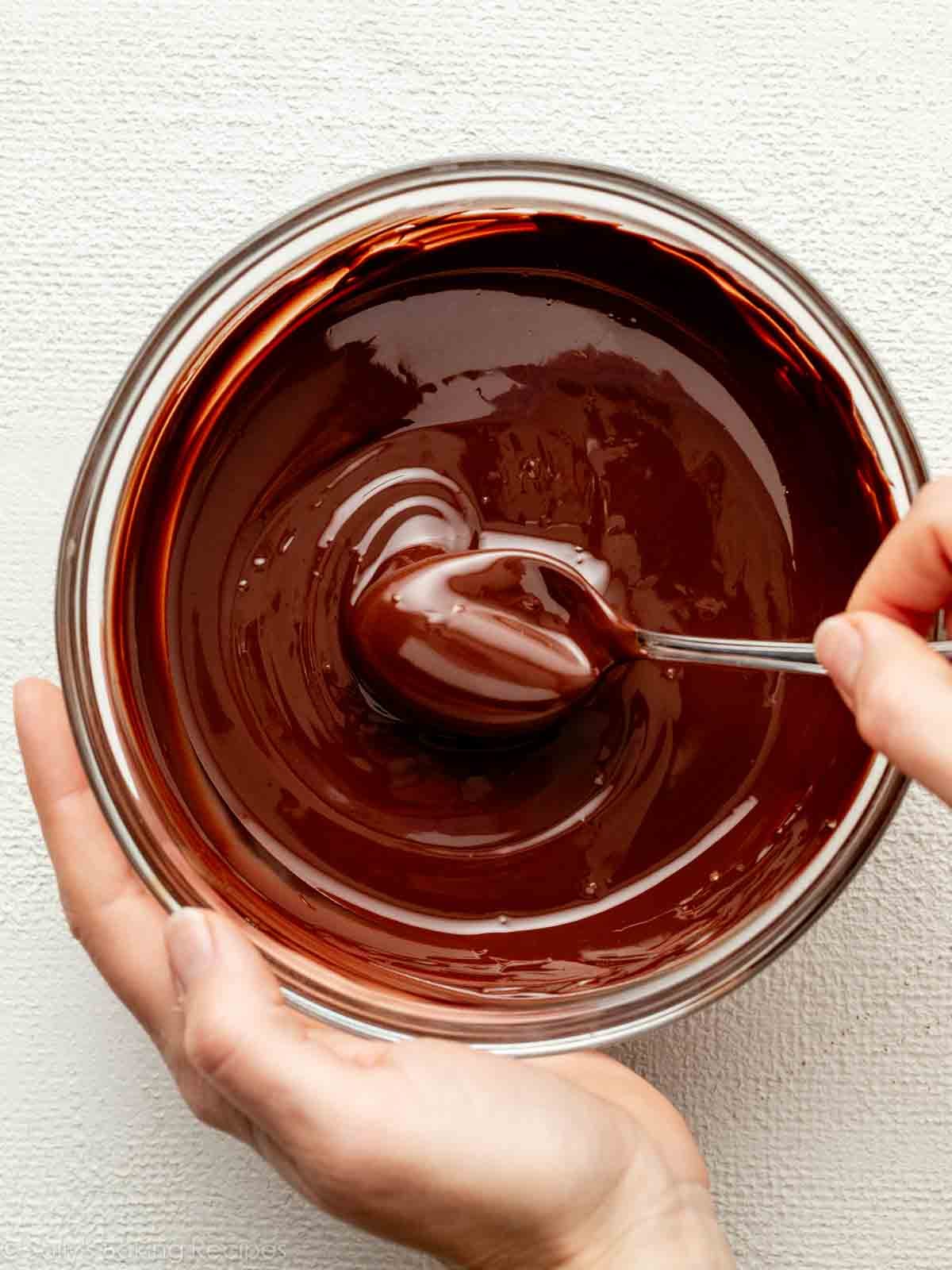 hand stirring melted chocolate in bowl.