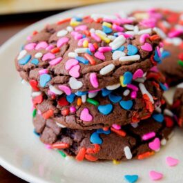 stack of chocolate cake mix cookies with sprinkles on a white plate