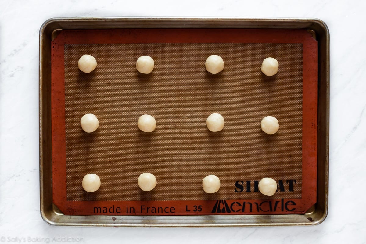 Sugar cookie dough balls on baking Silpat baking mat before baking
