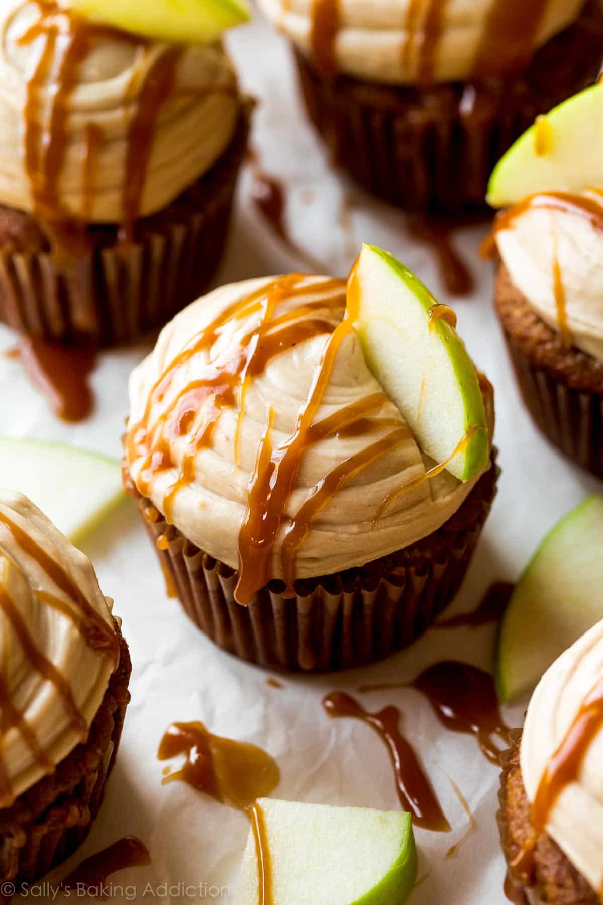apple spice cupcakes with salted caramel frosting, a drizzle of salted caramel, and a slice of granny smith apple on top