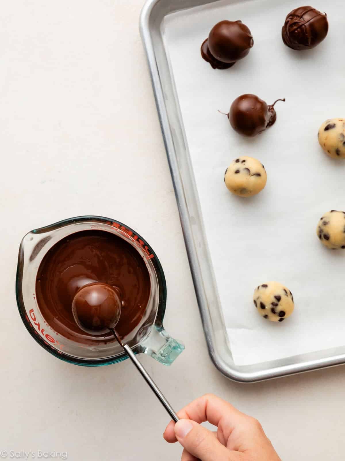 hand dipping dough ball in chocolate.