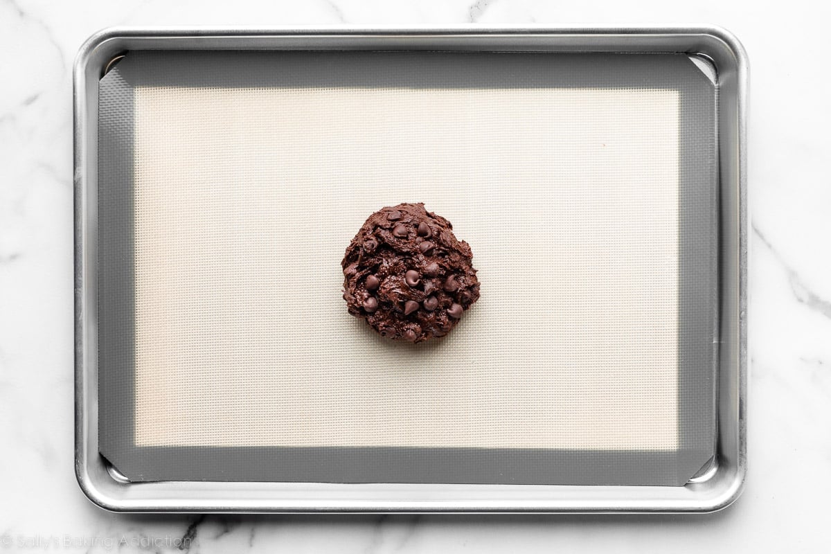 mound of chocolate cookie dough in center of lined baking sheet.