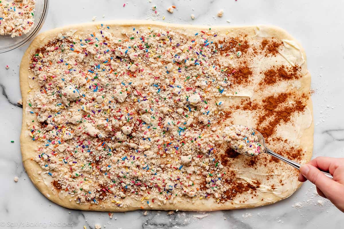 spoon sprinkling sprinkle crumble filling on buttered dough.