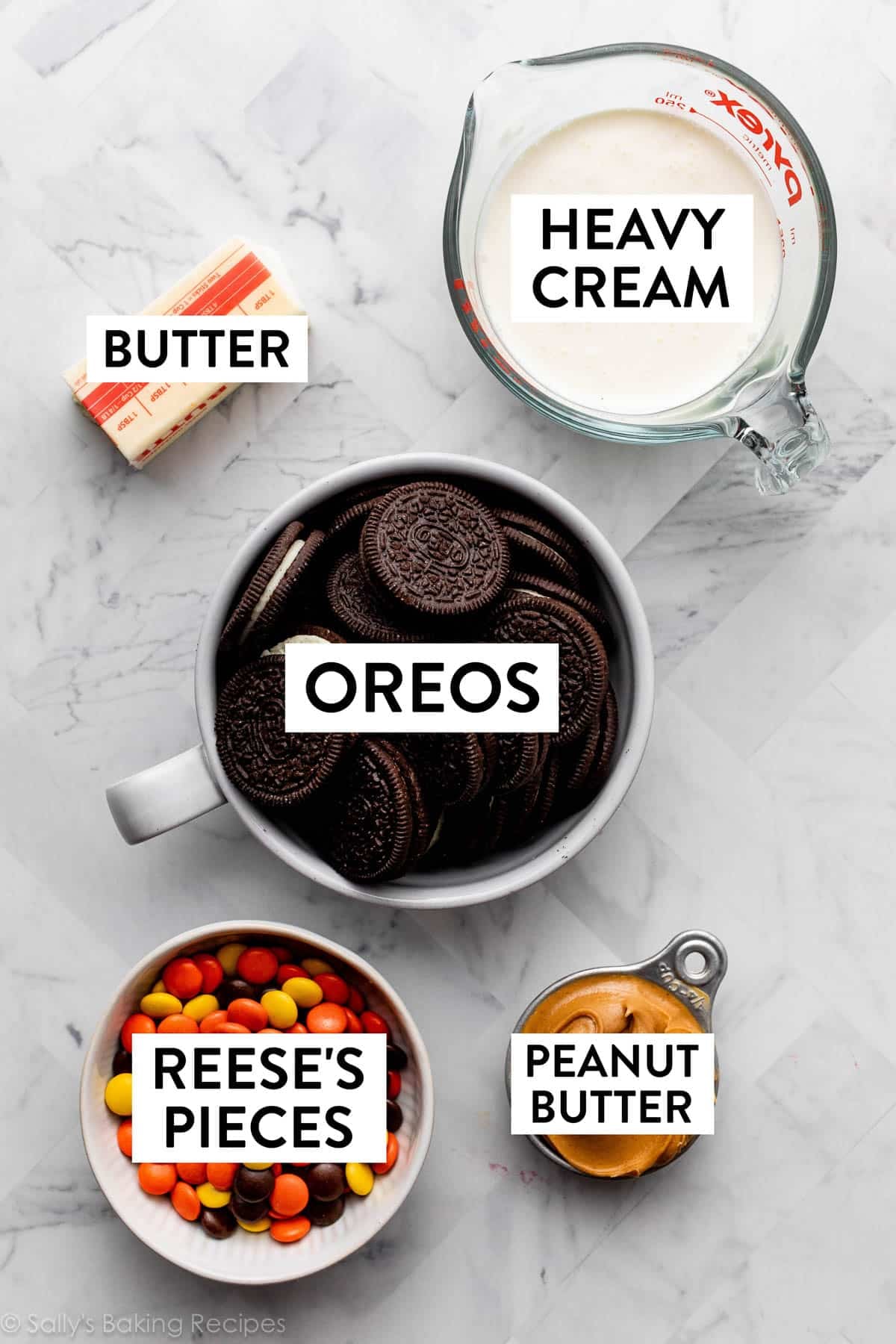 Oreos, heavy cream, Reese's Pieces, peanut butter, and butter on marble counter.