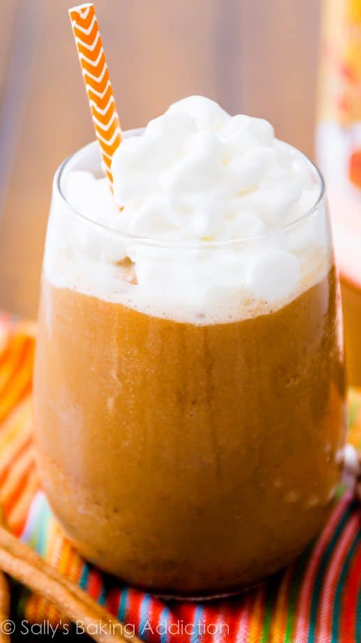 pumpkin frappuccino in a glass with whipped cream and a straw