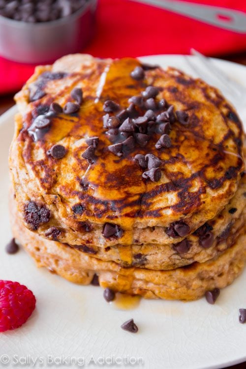 stack of whole wheat oatmeal chocolate chip pancakes with maple syrup on a white plate