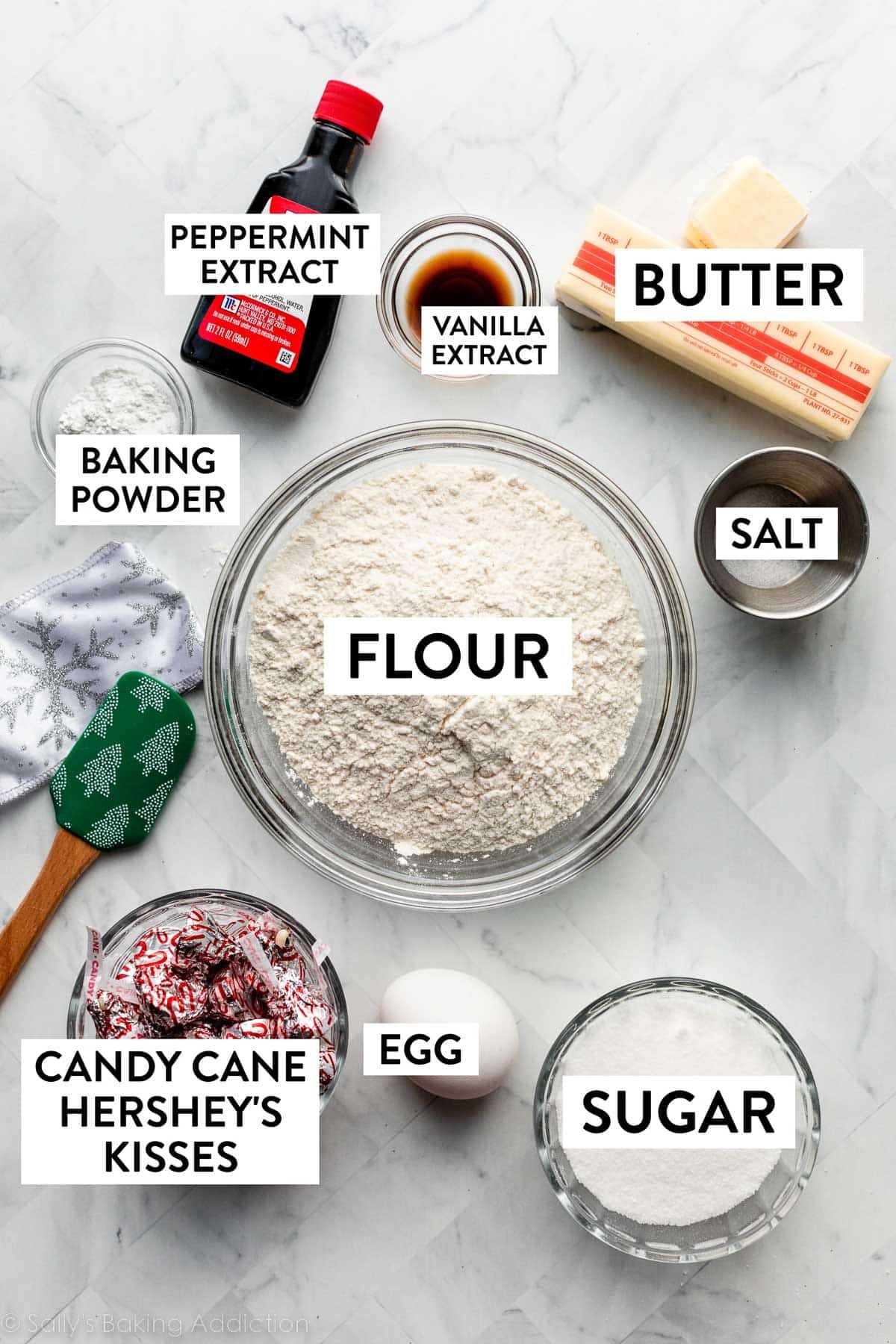 ingredients on counter including flour, butter, vanilla, salt, egg, sugar, and a bowl of candy cane flavored Hershey's Kisses.