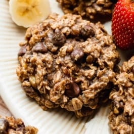 banana chocolate chip breakfast cookie on plate with strawberry and banana slices.