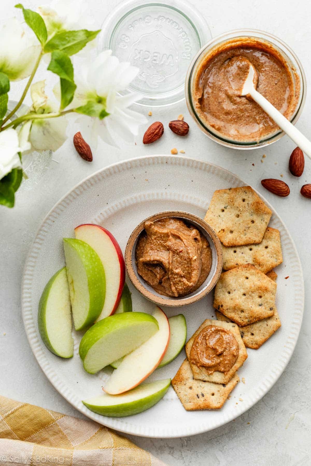 almond butter in small ramekin on plate with crackers and apple slices.