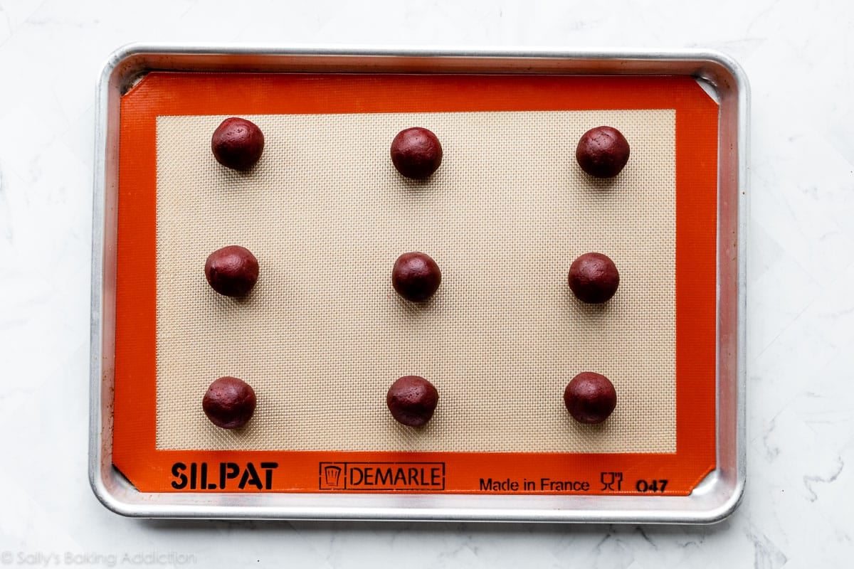 red velvet cookie dough balls on lined baking sheet
