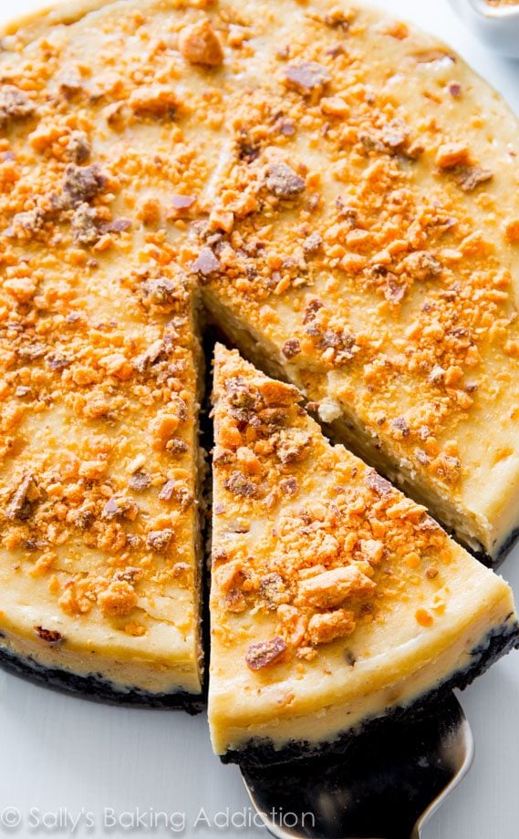 peanut butter Butterfinger cheesecake with a slice cut and placed on a dessert server
