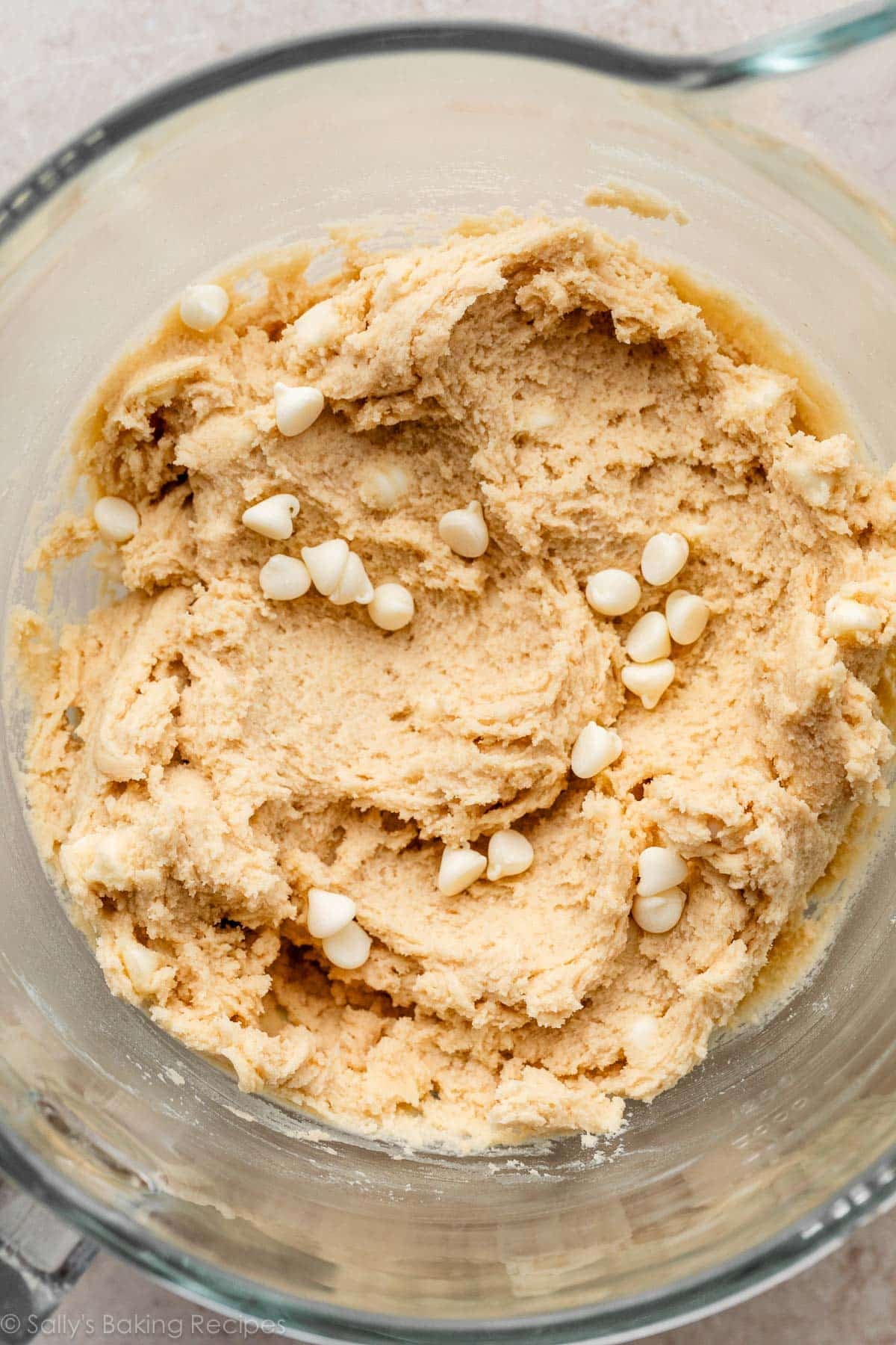 creamy cookie dough with white chocolate chips in glass bowl.