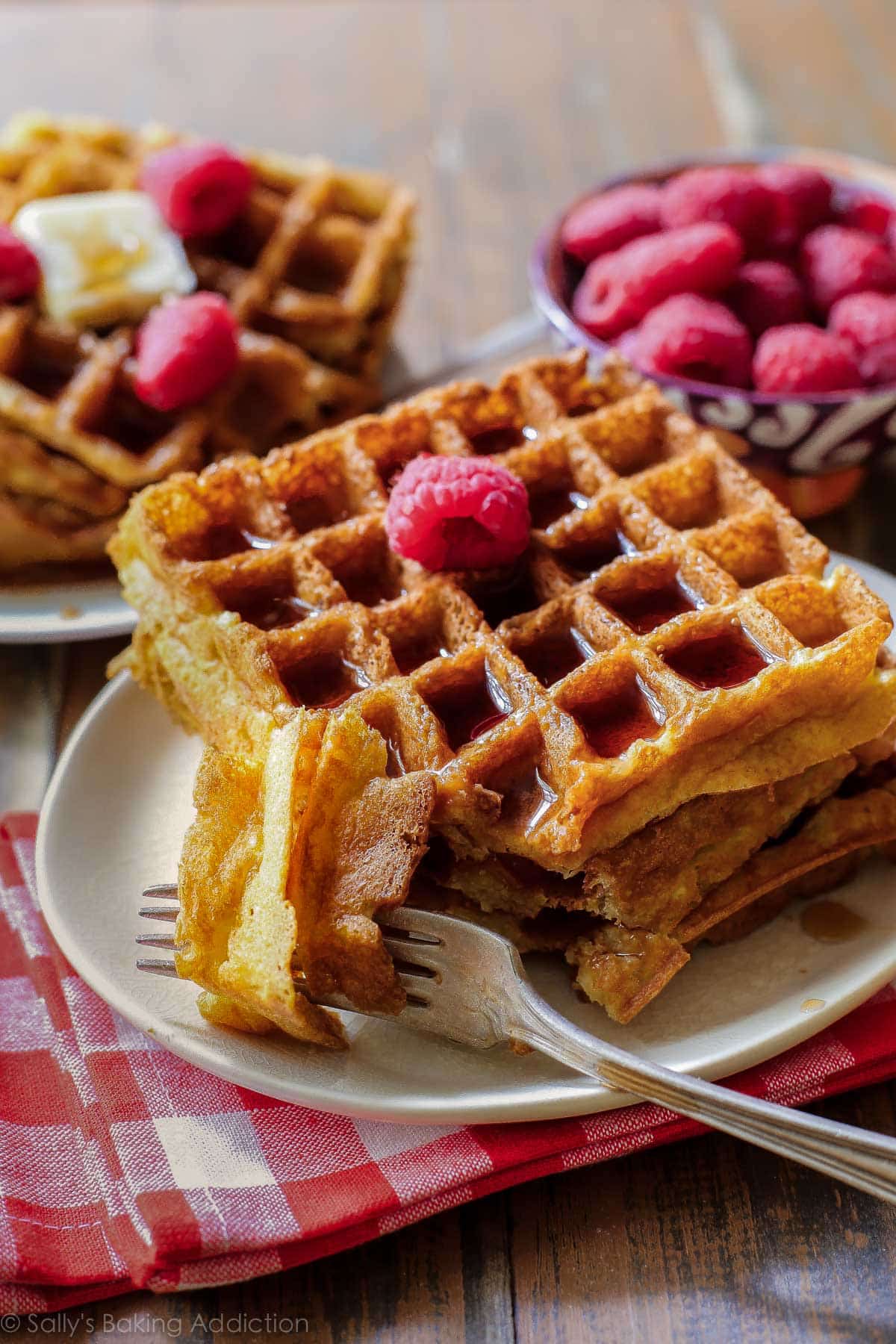stack of buttermilk waffles with raspberries on a cream plate