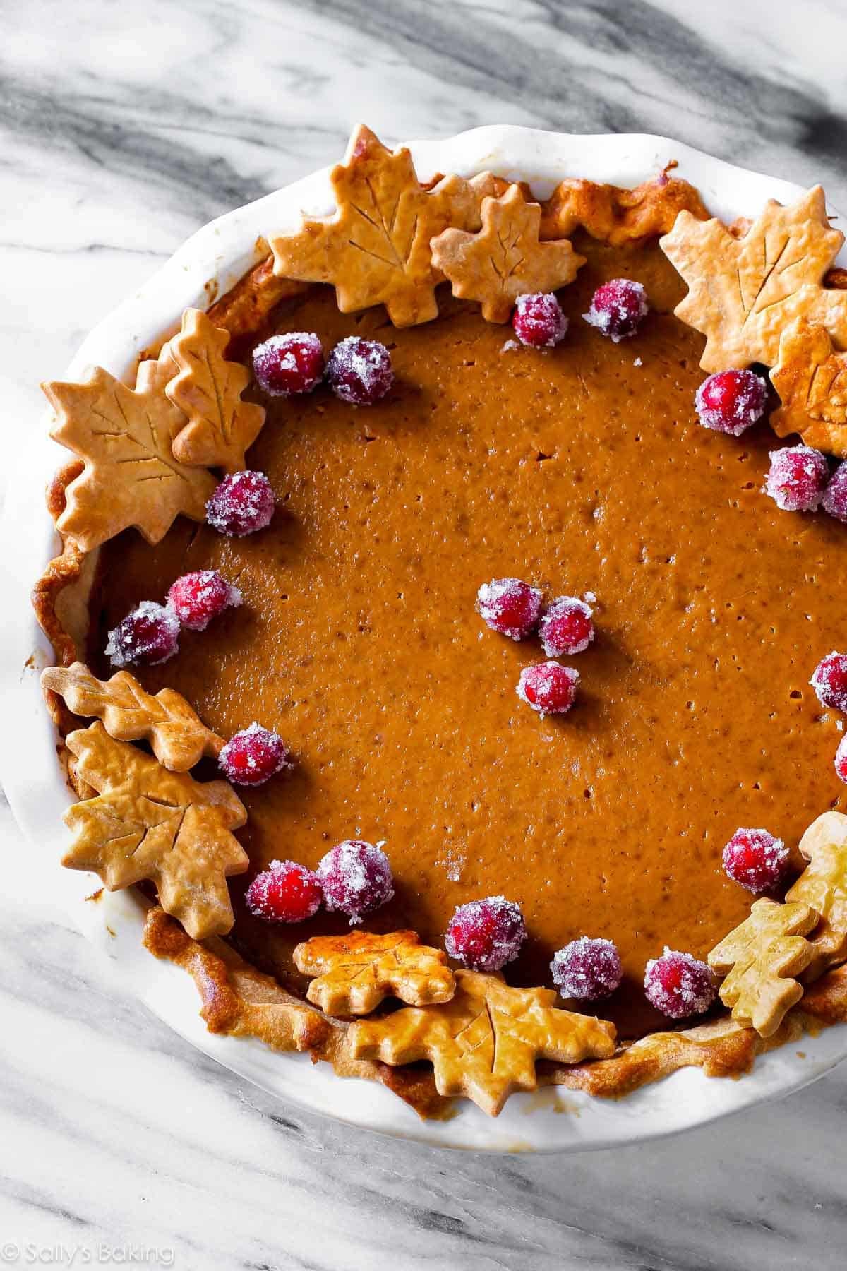 pumpkin pie with leaf pie shapes and sugared cranberries.