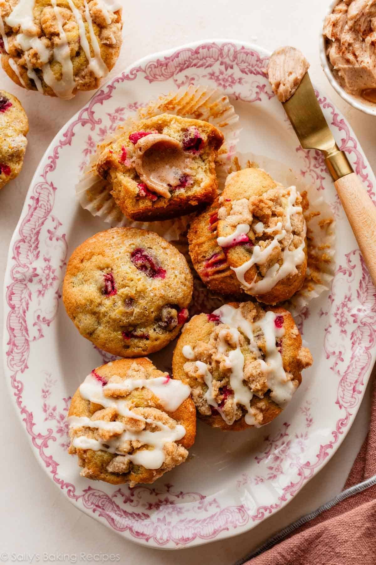 cranberry orange muffins on pink floral serving plate with cinnamon butter on a halved muffin.