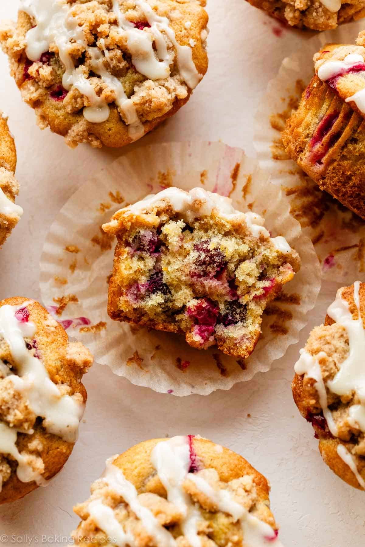 iced cranberry orange muffins with one broken in half to show cranberry center.