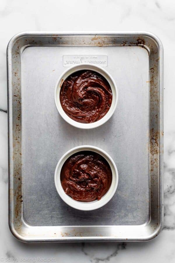 two ramekins of cake batter on small baking sheet.