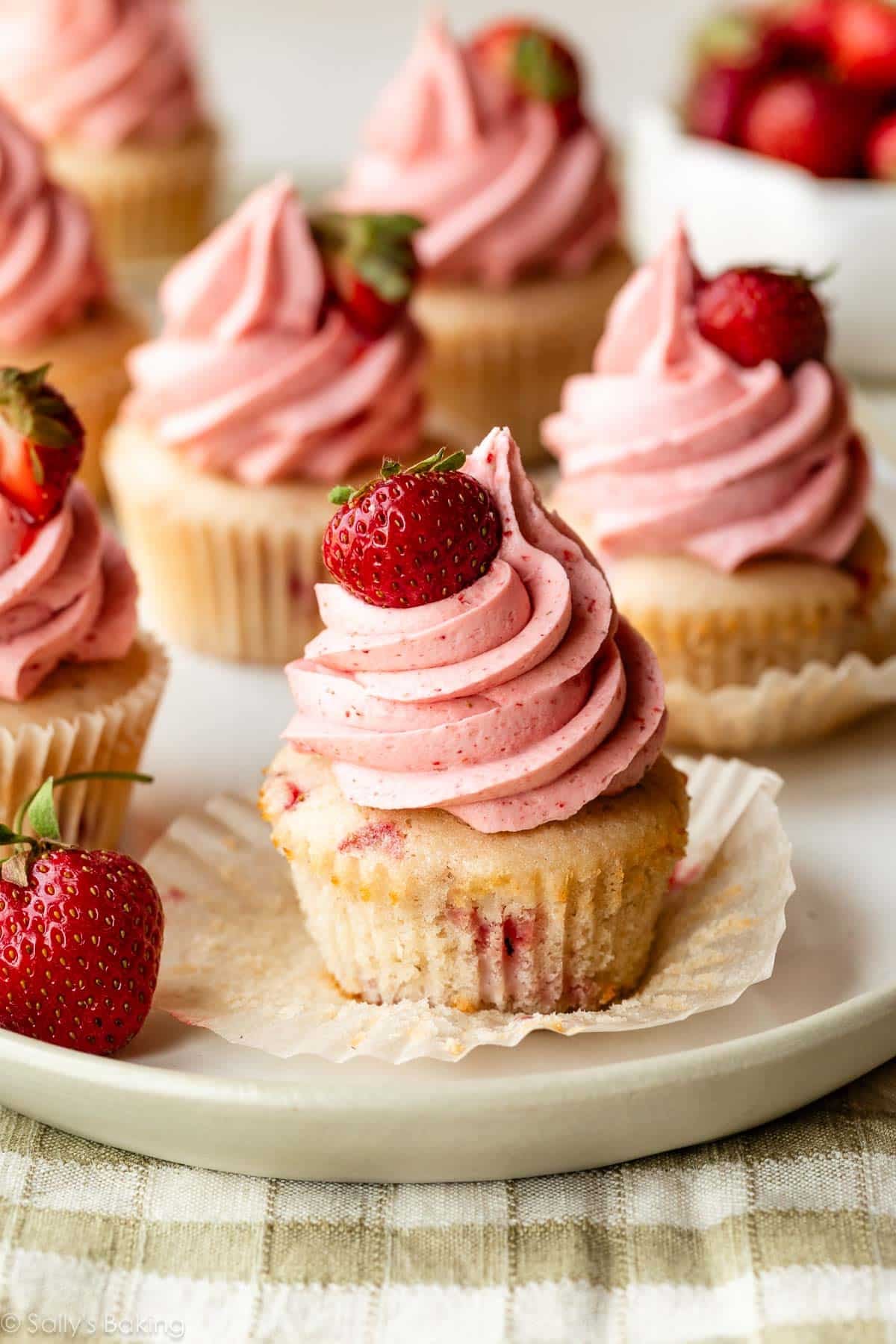 strawberry cupcakes with naturally flavored strawberry buttercream with a fresh strawberry on top.