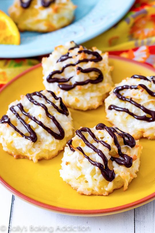 orange macaroons with chocolate drizzle on a yellow plate