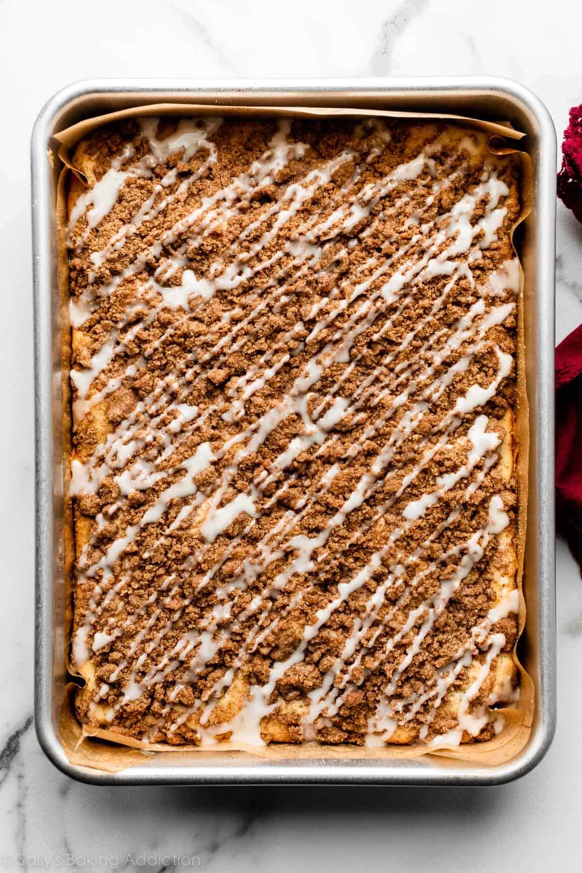 overhead photo of cinnamon coffee cake with crumb topping and vanilla icing drizzled on top.