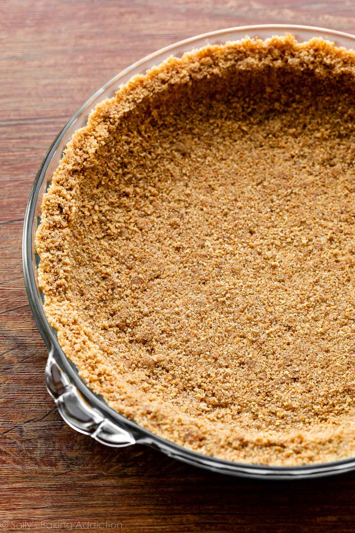 close-up photo of graham cracker crust pressed into glass pie dish.