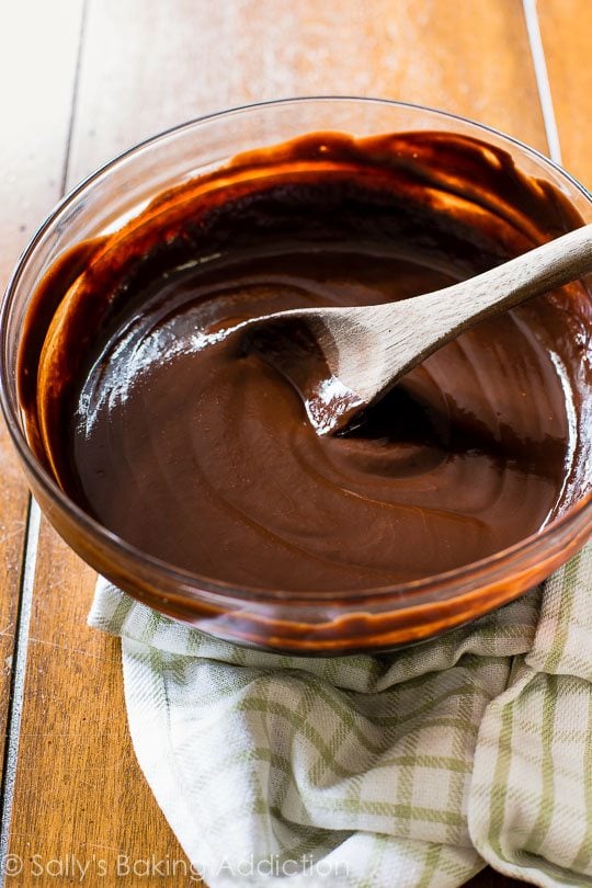 chocolate ganache in a glass bowl with a wood spoon