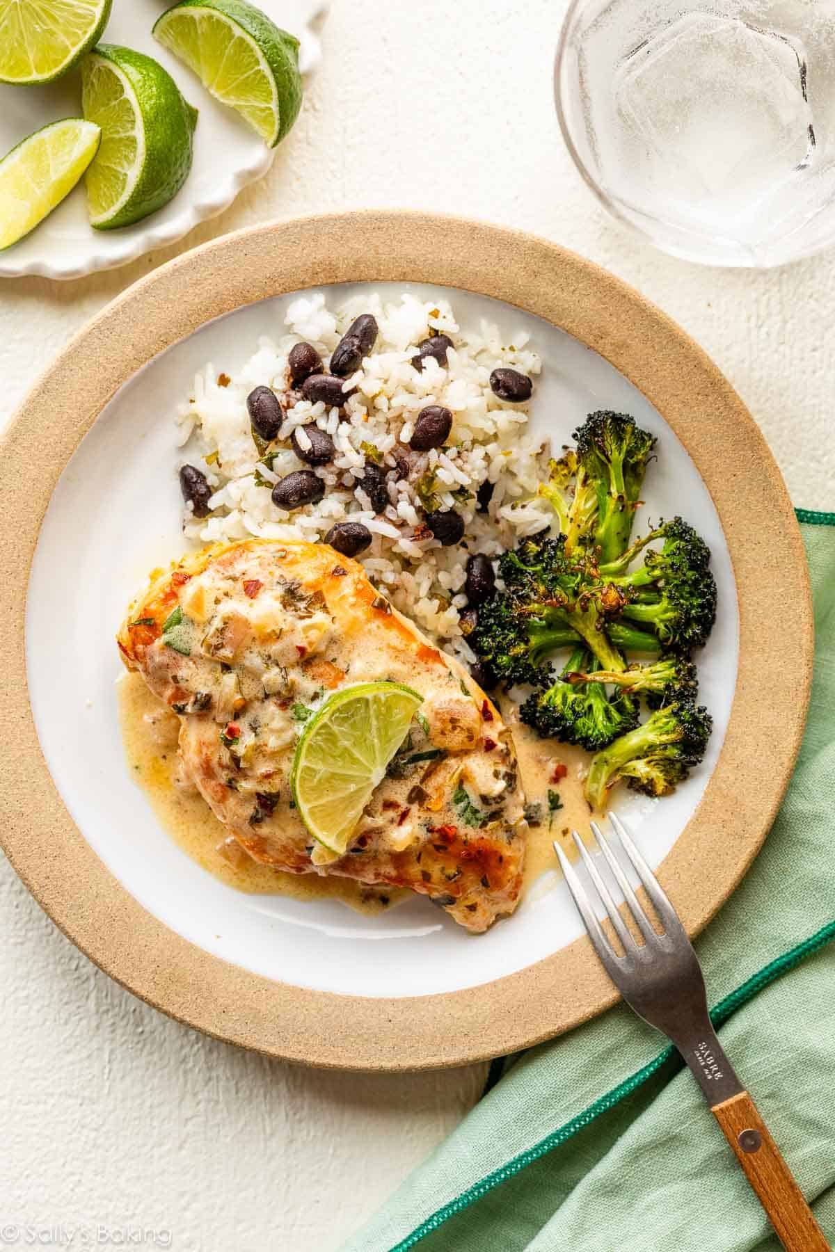plate with roasted broccoli, white rice and black beans, and cilantro lime chicken with creamy sauce on top.