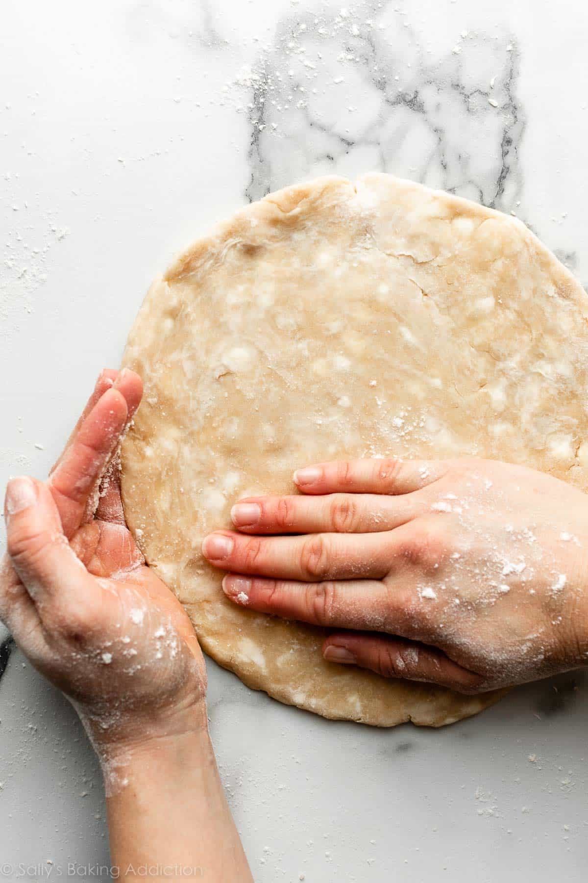 hands shaping edges of rolled out dough.
