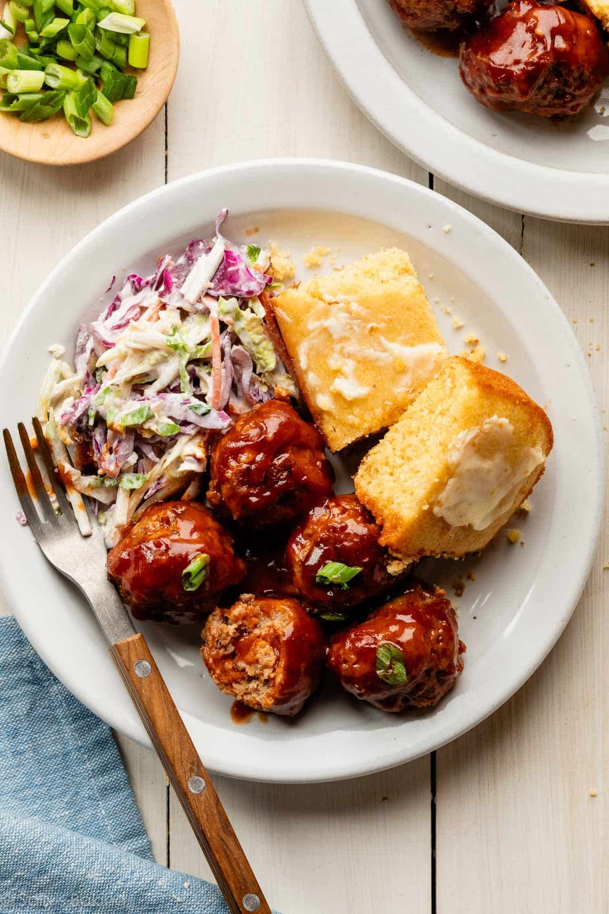 bbq meatballs on plate with cornbread and coleslaw.