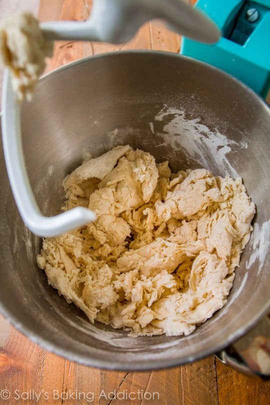 bagel dough in a metal stand mixer bowl with dough hook attachment