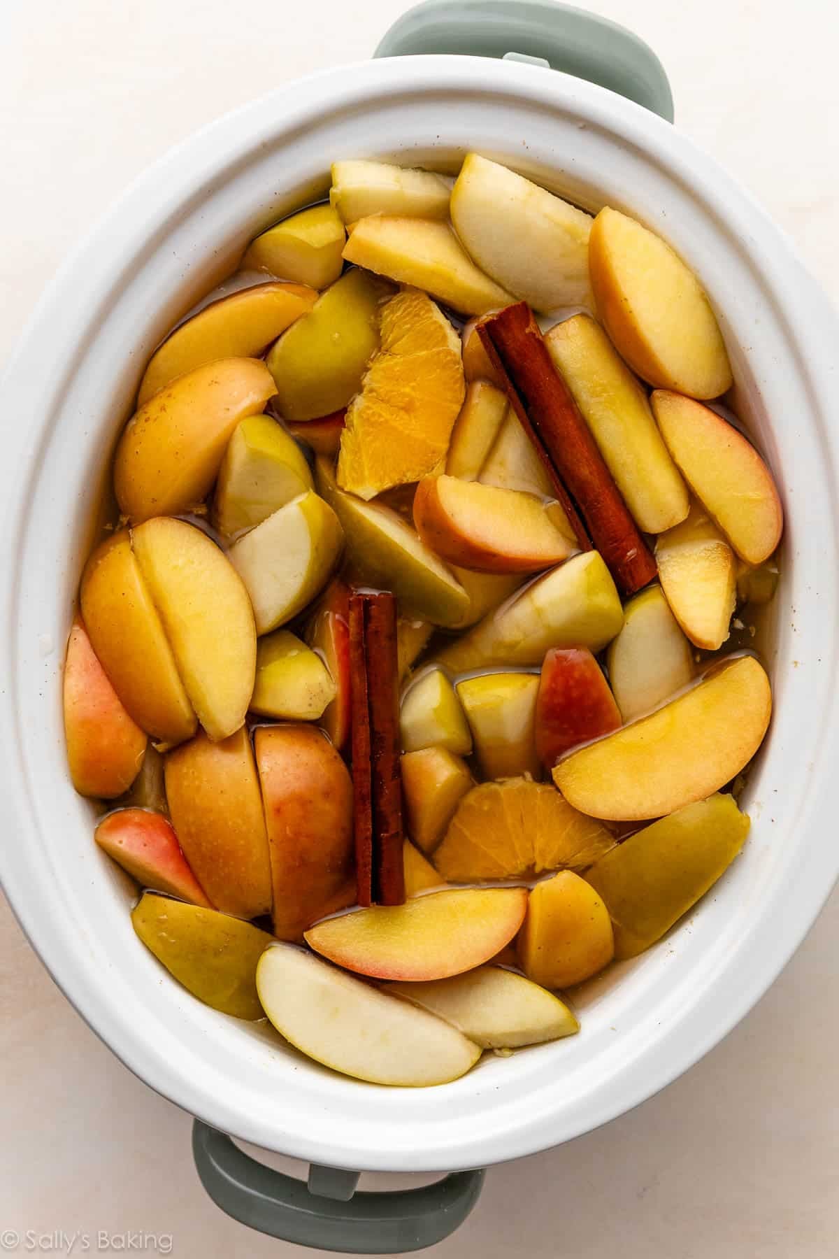 cooked apple slices and cinnamon sticks in slow cooker.