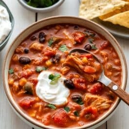 bowl of slow cooker chicken chili with sour cream on top.