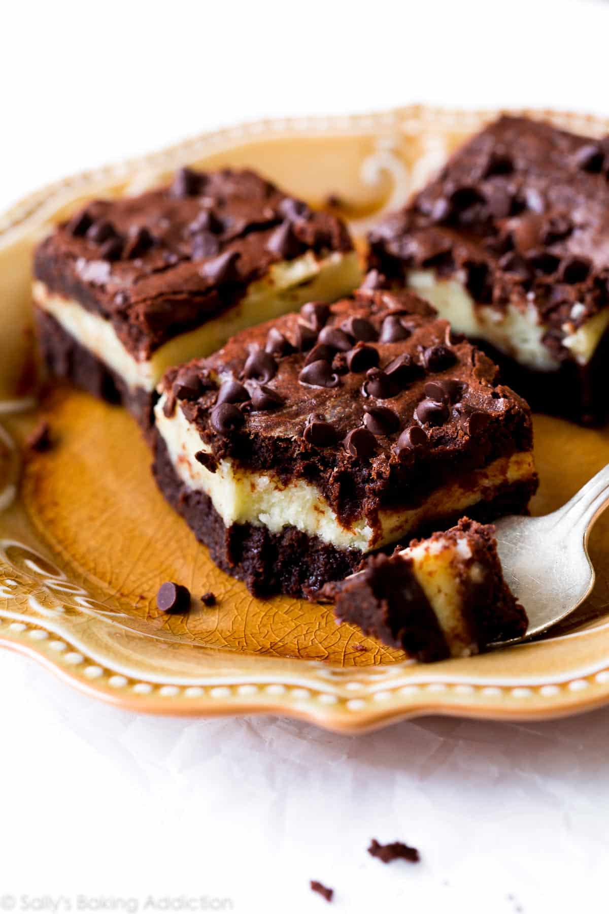mocha cheesecake brownies on a gold plate with a fork