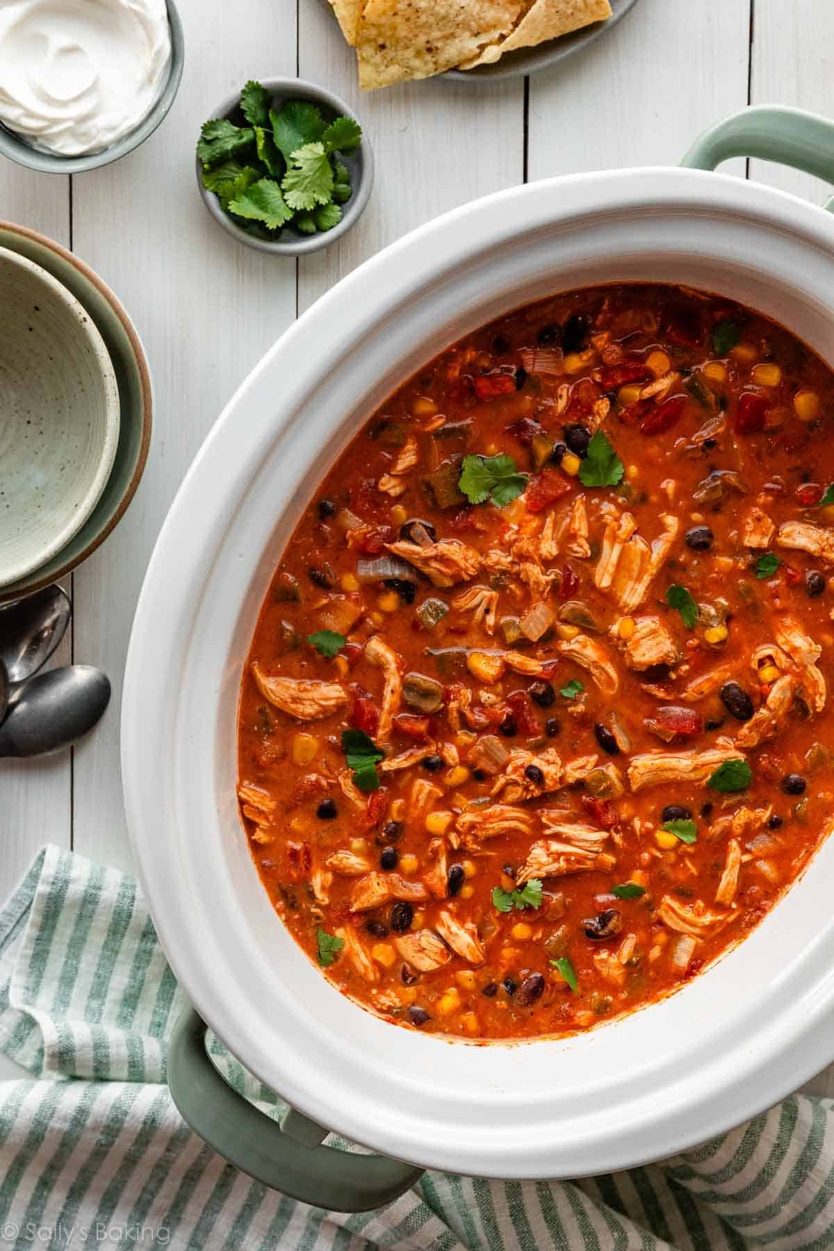 chicken chili in slow cooker with blue striped towel under it.
