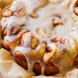 slow cooker cinnamon rolls with maple icing on parchment paper
