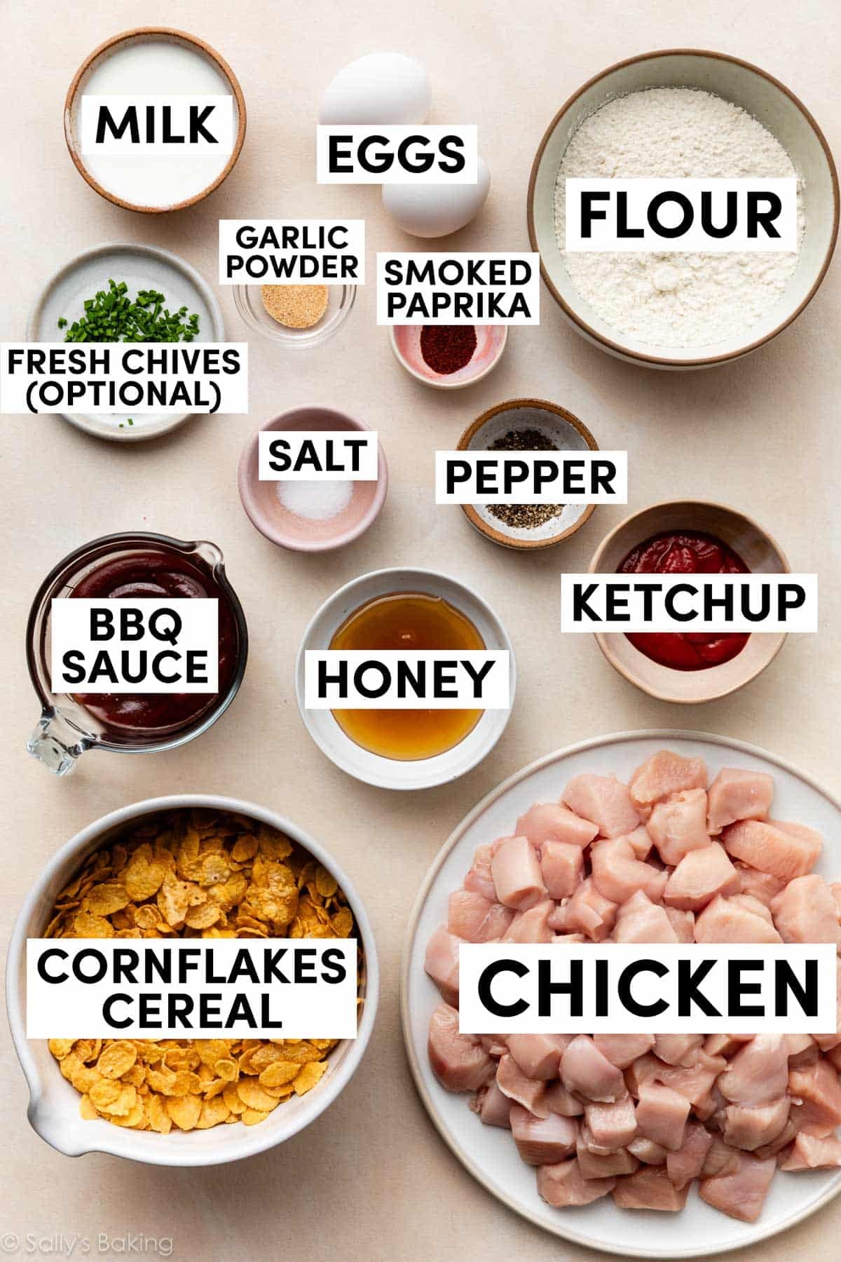 ingredients in bowls including bbq sauce, cornflakes cereal, flour, milk, honey, ketchup, spices, and eggs.
