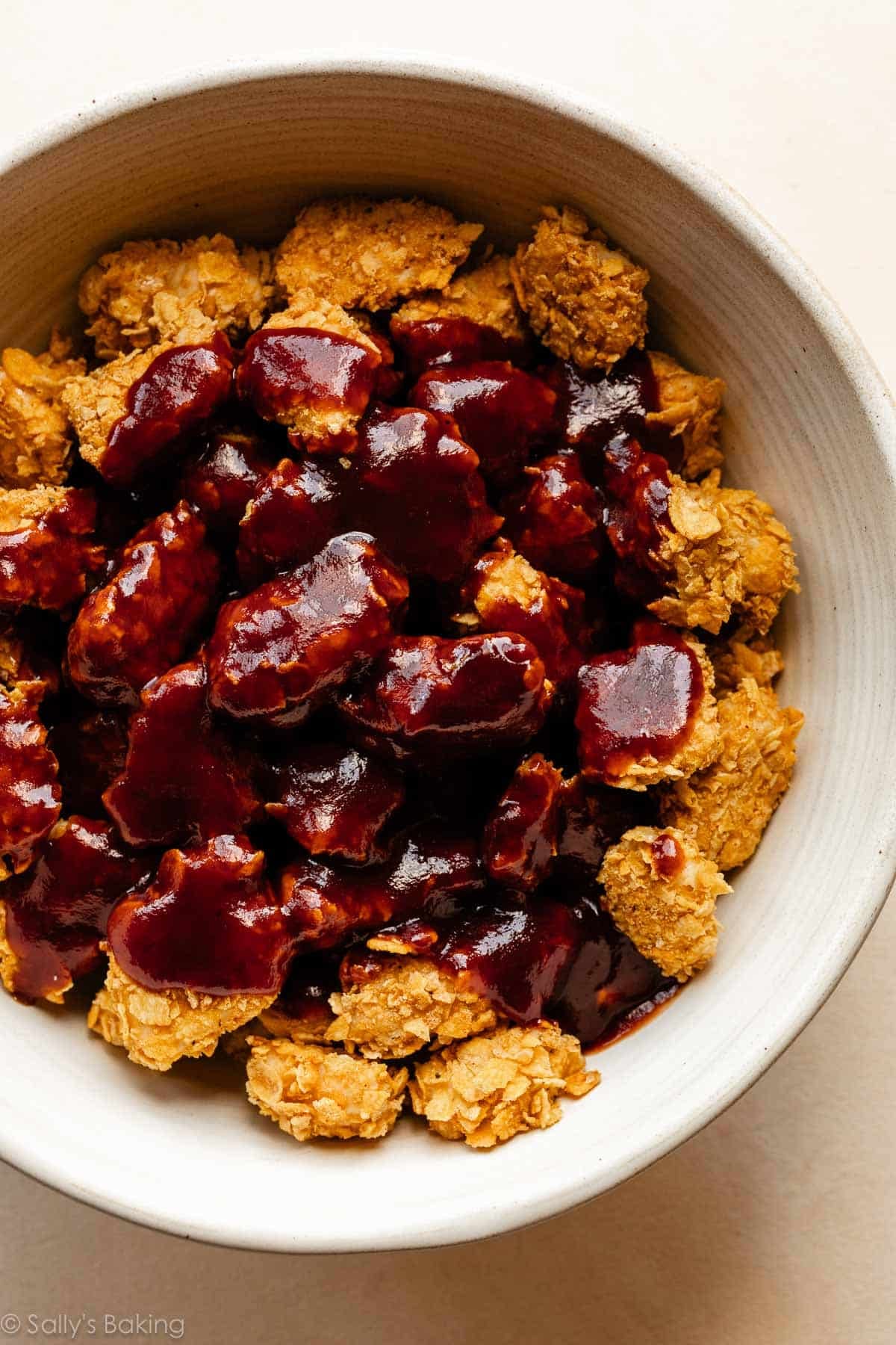 honey bbq sauce poured on top of cooked coated chicken.