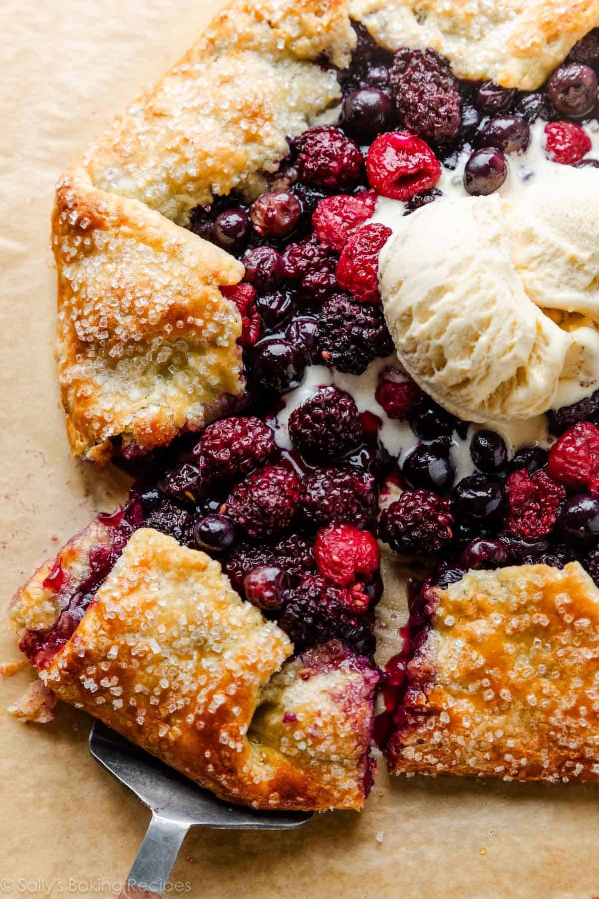 sliced mixed berry galette with melted vanilla ice cream on top.
