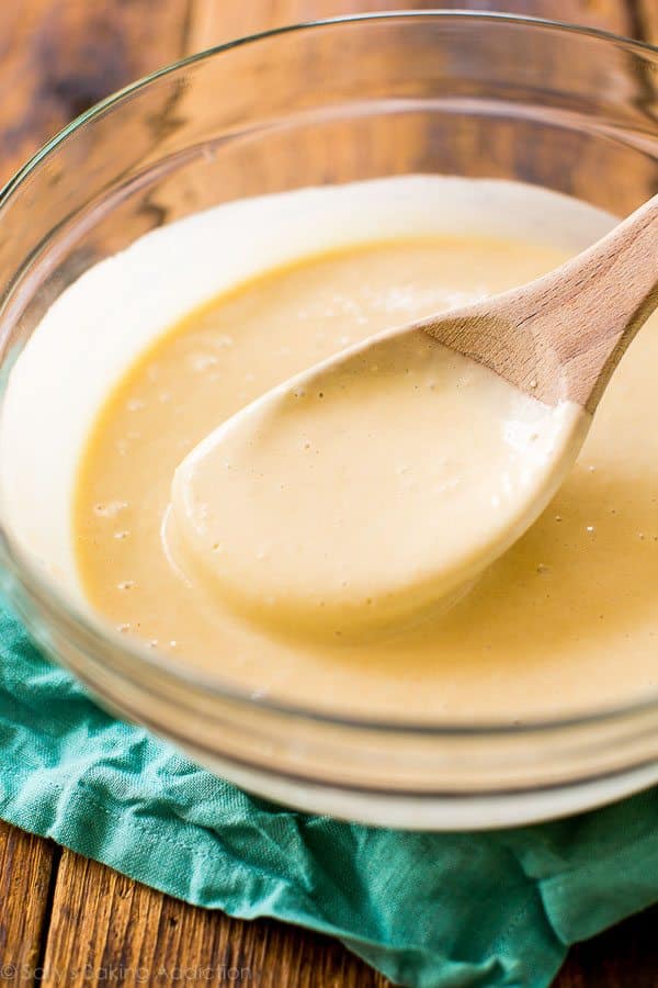 funnel cake batter in a glass bowl with a wood spoon