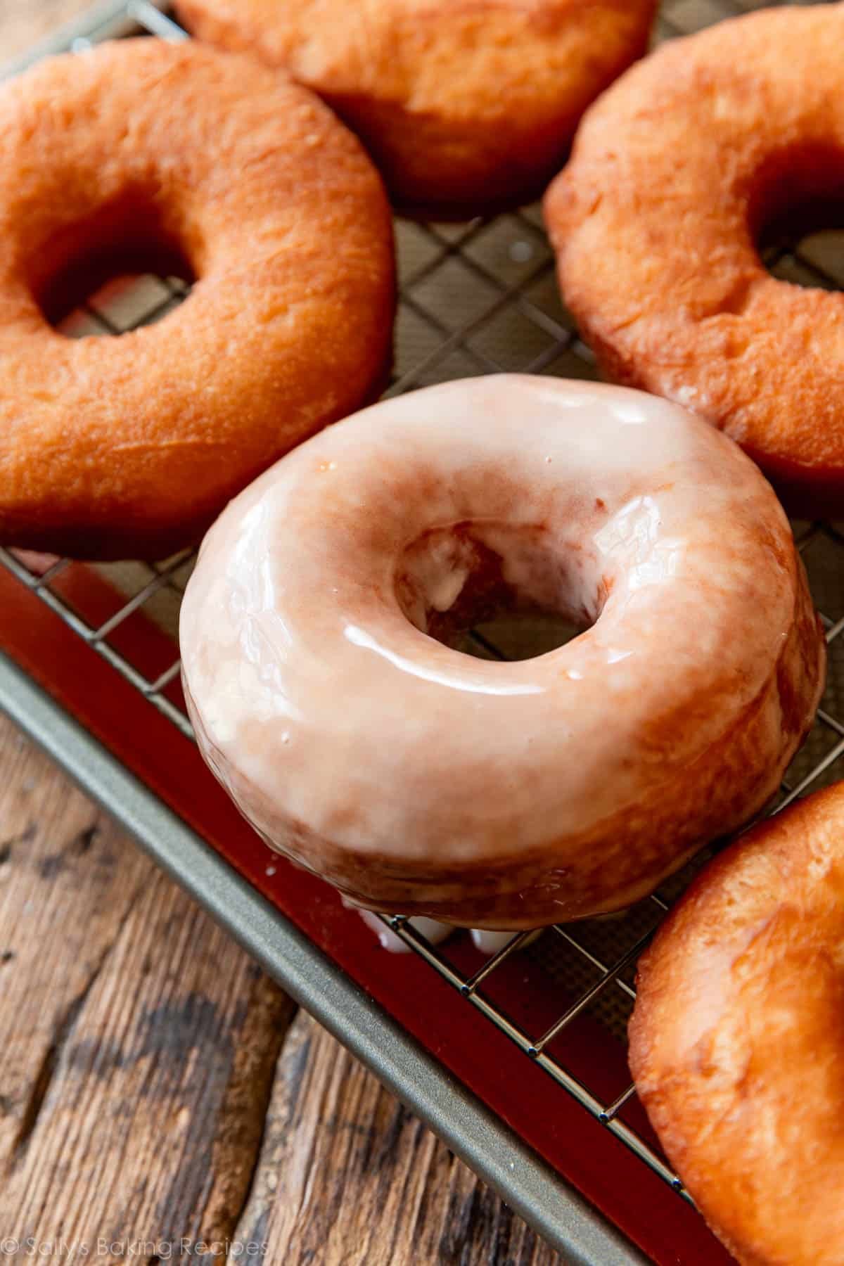 glazed doughnut on wire cooling rack on top of baking sheet.
