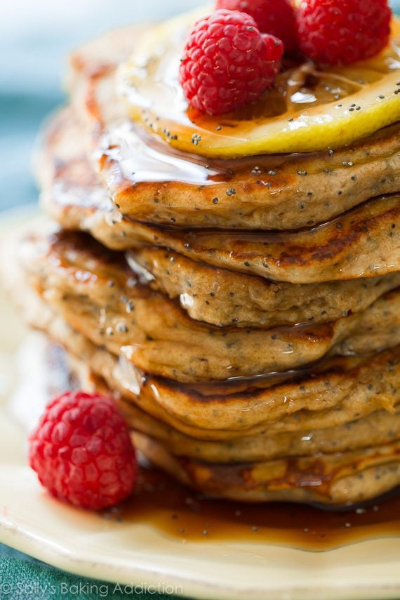 stack of lemon poppy seed pancakes with maple syrup on a cream plate