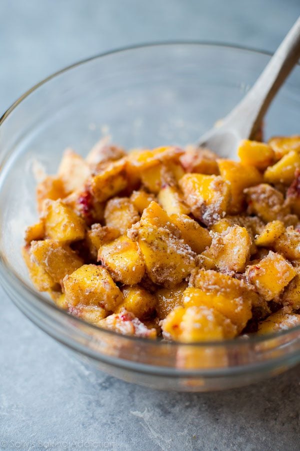 peach filling in a glass bowl with a wood spoon