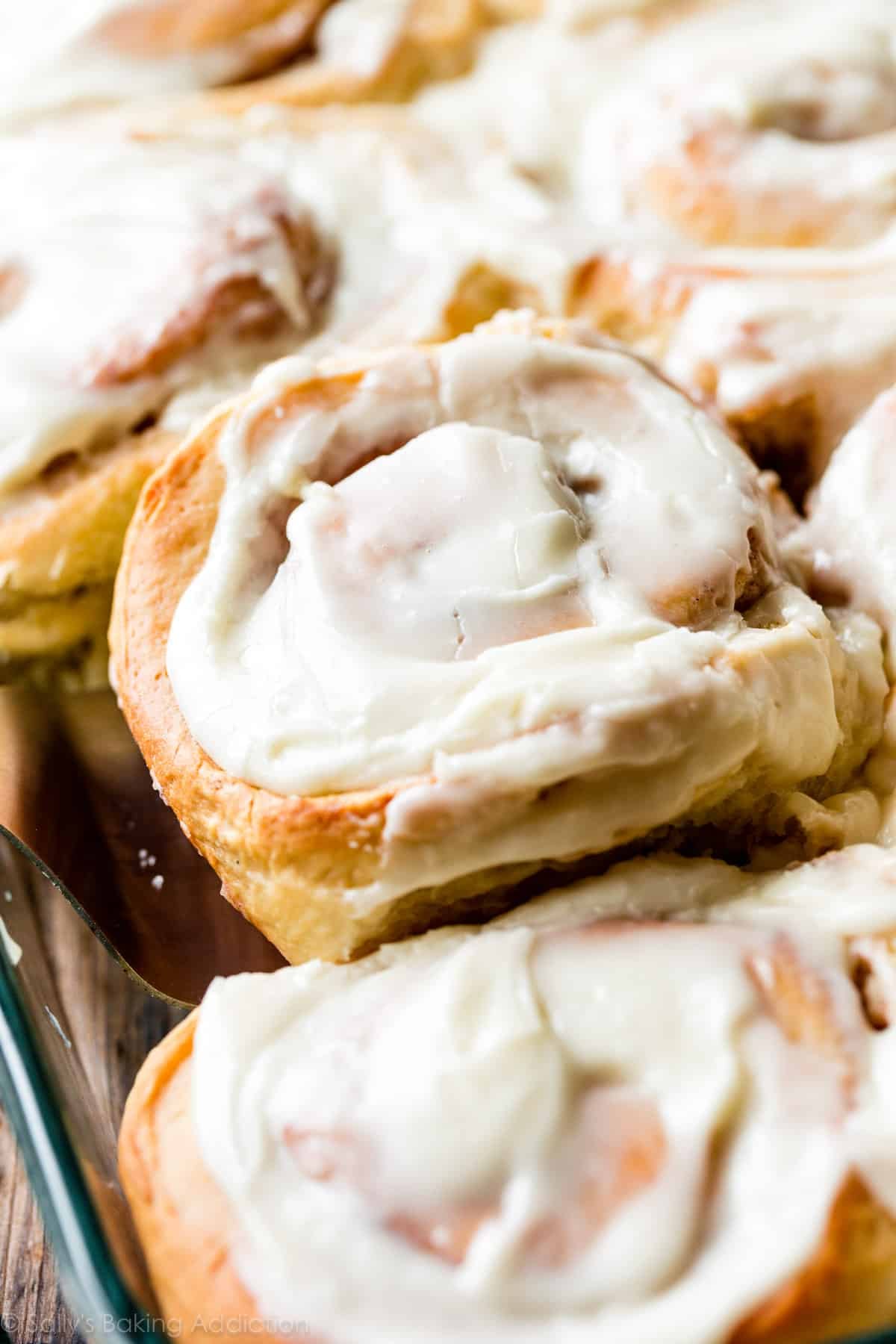 close up photo of a big cinnamon roll being scooped out of the pan