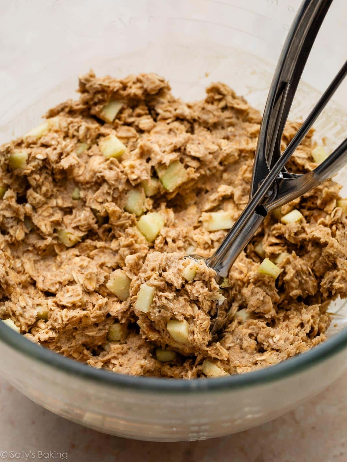 apple cookie dough in glass bowl with cookie scoop.