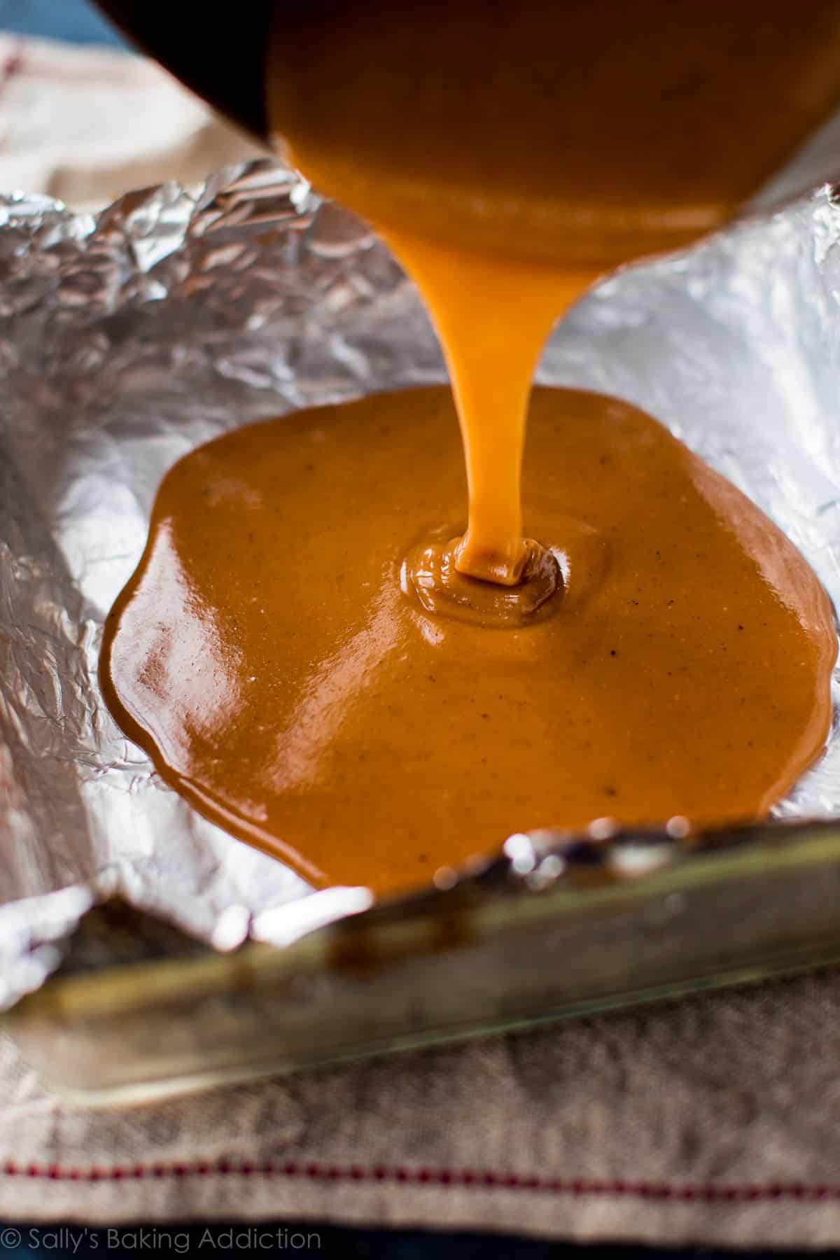 pouring sea salt vanilla caramel liquid into a baking dish lined with aluminum foil