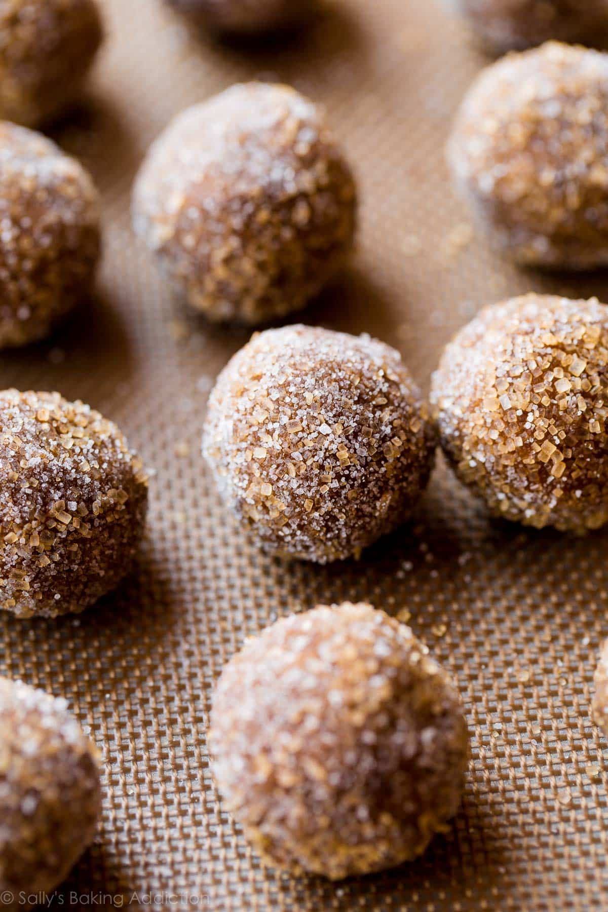 cookie dough balls rolled into coarse sugar and placed on a baking sheet