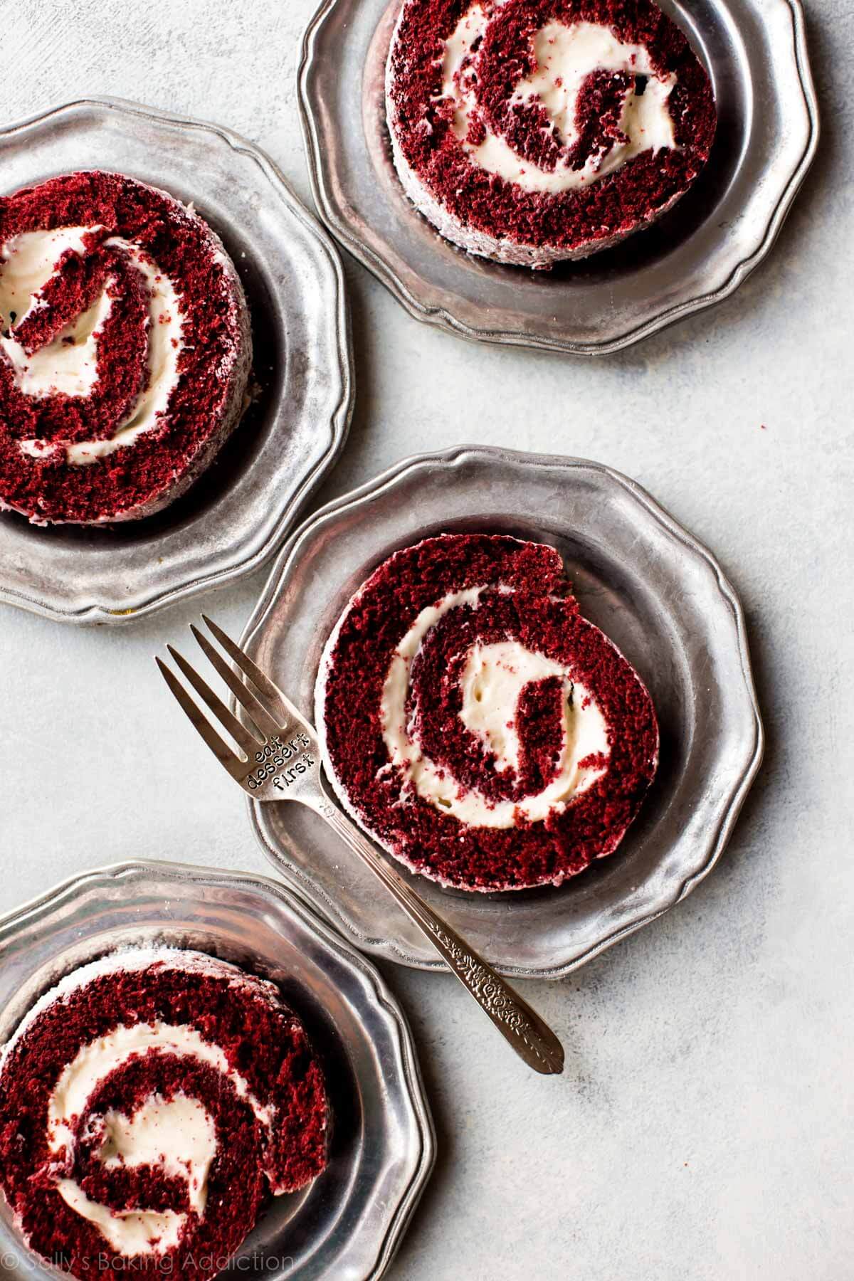 overhead image of slices of red velvet cake roll on silver plates