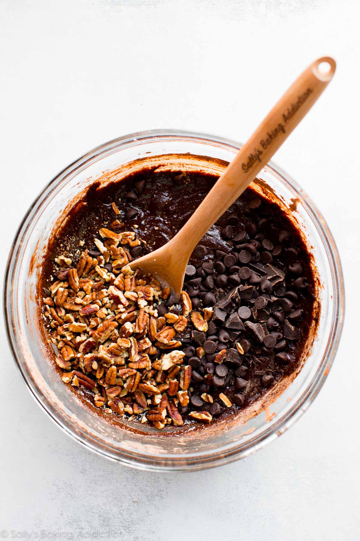 turtle brownie batter in a glass bowl with a wood spoon